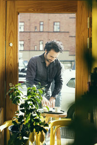 Barista working at sidewalk cafe seen through glass door