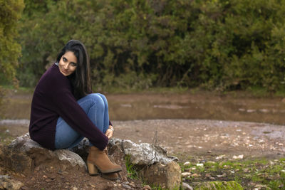 Portrait of smiling young woman sitting on rock