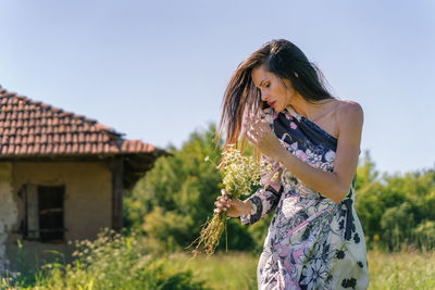 Woman holding umbrella standing on field