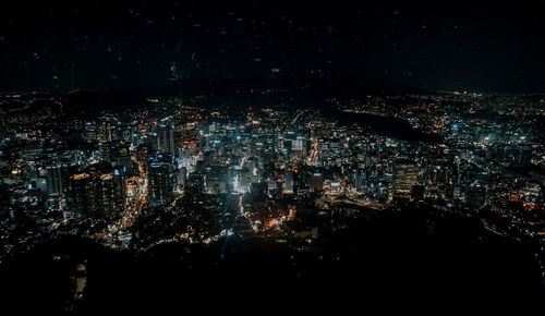 High angle view of illuminated city against sky at night