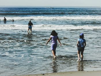 People walking on beach against sea