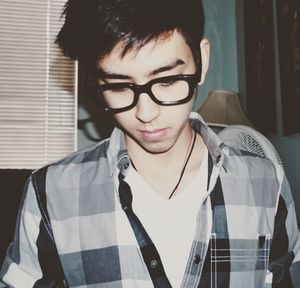 Close-up of young man wearing eyeglasses and plaid shirt at home