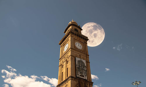 Low angle view of clock tower amidst buildings against sky