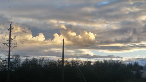 Low angle view of electricity pylon against cloudy sky