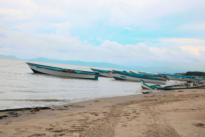 Boat moored on beach against sky