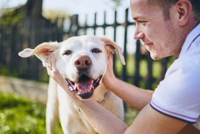 Smiling man stroking dog in lawn