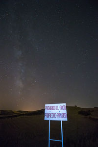 Information sign on landscape against sky at night