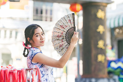 Portrait of smiling teenager girl holding hand fan