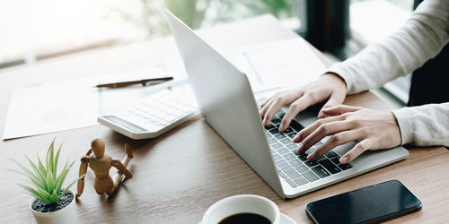 Midsection of woman using laptop on table