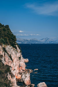 Scenic view of sea and rocks against blue sky