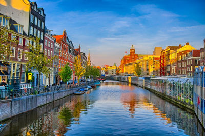 Bridge over river amidst buildings in city against sky