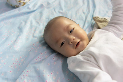 High angle view of baby lying on bed