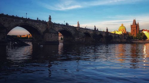 Arch bridge over river against buildings in city