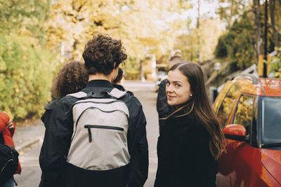 Portrait of teenage girl walking with male and female friends on road in city