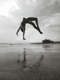 Man jumping in sea against sky