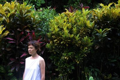 Portrait of smiling young woman standing against plants