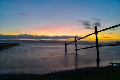 Silhouette person standing on beach against sky during sunset