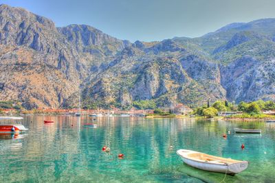 Boats moored in sea with mountains in background