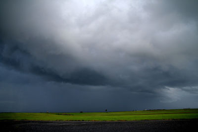 Scenic view of agricultural field against storm clouds