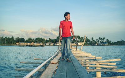 Full length of man standing on wooden planks over lake