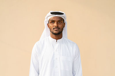 Portrait of young man standing against yellow background