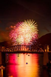 Firework display over river against sky at night