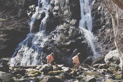 Women against waterfall in forest