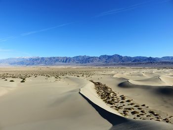 Scenic view of desert against clear blue sky