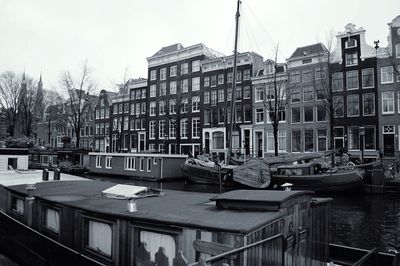 Boats moored in city against sky