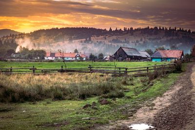 Houses in farm against sky at sunset