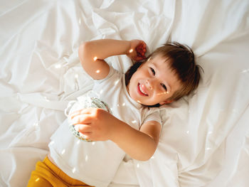 Little boy plays with sparkling mirror disco ball in bed and laughing happily. playful child.