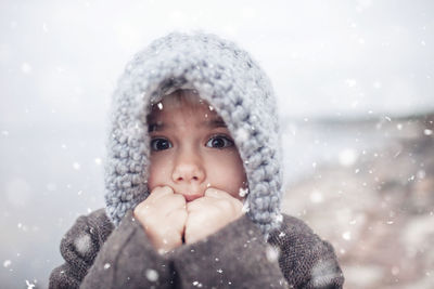 Girl in knitted grey hat hugging her frozen smaller brother