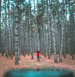 Man running on road amidst trees in forest