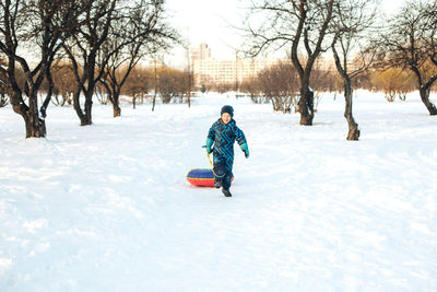 Full length of girl walking on snow covered land in city