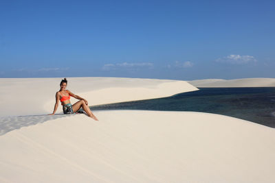 Happy young woman relaxing on a dune of lencois maranhenses, brazil