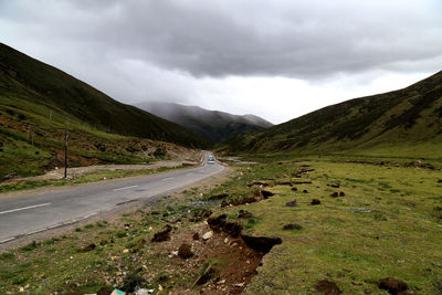 Scenic view of road by mountains against sky