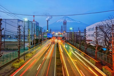 Light trails on road in city against sky