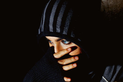 Close-up of man wearing mask against black background