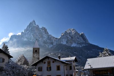 Houses by snowcapped mountains against blue sky