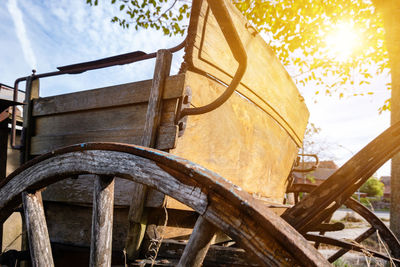 Close-up of wooden chairs against trees on sunny day