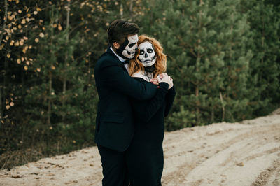 A couple in love is sitting hugging against the backdrop of mountains celebrating halloween in costu