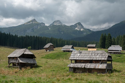 Houses on field by mountains against sky