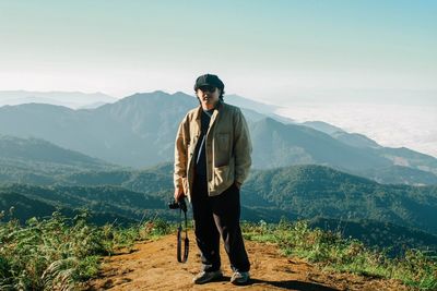 Young man standing on mountain against sky