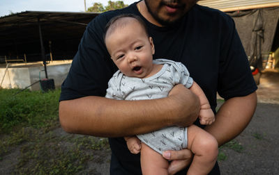 Midsection of father and baby on man