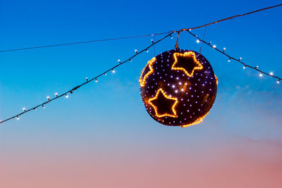 Low angle view of illuminated lights against clear blue sky