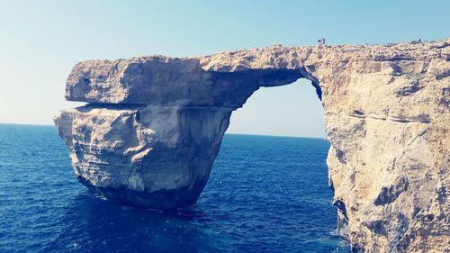 Rock formation in sea against clear sky