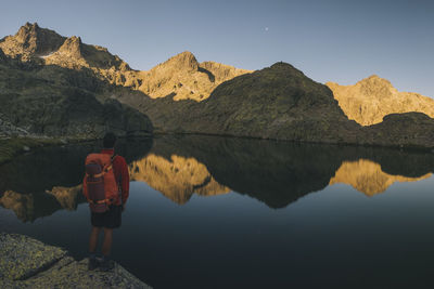 A young man with backpack looking at lake reflection, sierra de gredos