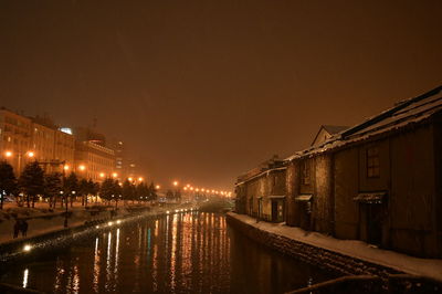 Illuminated bridge over river in city at night