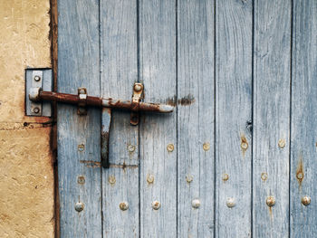 Close-up of rusty latch on closed wooden door