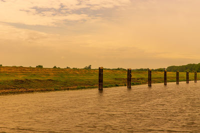 Wooden posts on field against sky during sunset